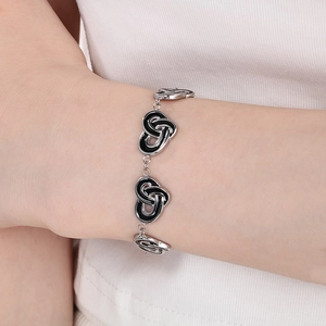 Gros plan détaillé d'un bracelet noeud argenté avec émail noir porté au poignet