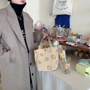 Close-up of beige corduroy tote bag with a black smiley face pattern in a cozy cafe setting