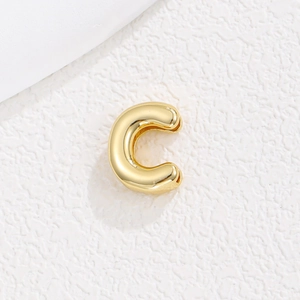 Detailed close-up of a glossy gold-plated C-shaped clip earring accessory with smooth finish