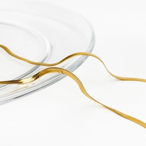 Detailed close-up of a golden flat snake chain necklace with sleek metallic luster