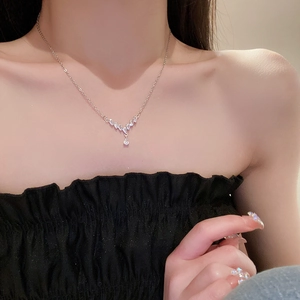 Detail of silver V-shaped necklace with teardrop zircon pendant on female model neck