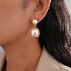 Retro faux pearl gold drop earrings with rhinestone square charms worn by a model