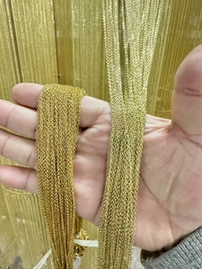 Close-up of DIY gold-plated jewelry chains held in hand for handmade necklace crafting