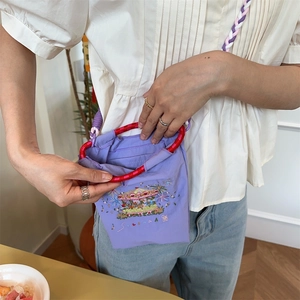 Detail of light purple canvas bag showing embroidery and woven shoulder strap texture