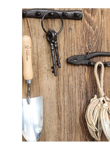 Close-up of vintage cast iron wall hooks with rustic tree branch texture and plier design