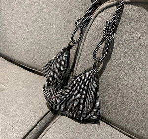 Close-up of sparkling silver rhinestones and unique knotted handle on a black evening bag