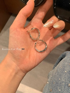 Close-up of minimalist silver hoop earrings with polished surface held in hand