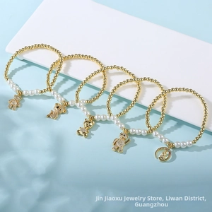 Detail of five-piece gold bear charm pearl elastic bracelet set on light blue background