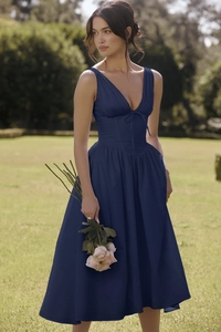 Close-up of deep blue V-neck dress with corset waist, bow tie detail and pleated skirt