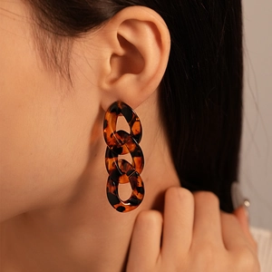 Close-up of model wearing acrylic leopard chain earrings in retro geometric style