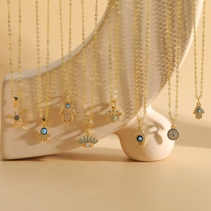 Detail von vergoldeten Evil Eye und Hamsa Halsketten mit Zirkonia auf Keramikständer