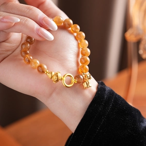 Dettaglio del bracciale con perline di citrino giallo e ciondoli a loto e campanella