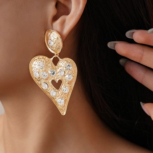 Détail de la boucle d'oreille cœur doré avec texture martelée et petits cristaux