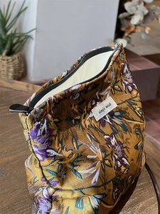 Close-up of caramel floral jacquard makeup bag with metal zipper and simple wish label