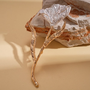 Detailed macro view of two-tone metallic flower brooch with silver petals and gold stem