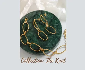 Detail of gold geometric link necklace and earrings on green marble display base