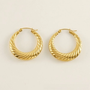 Macro detail of 18K gold-plated croissant hoop earrings with textured spiral design