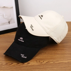 Detailed close-up of embroidered baseball caps in black and cream with distressed brim texture