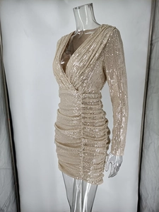 Detailed view of champagne gold sequined dress featuring deep V-neck and ruched fabric texture