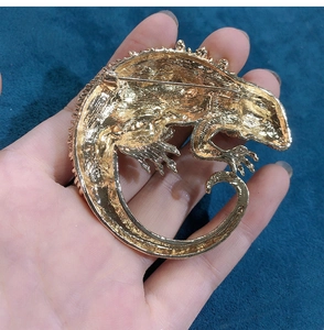 Macro detail of the gold-plated chameleon brooch showing textured scales and pin closure