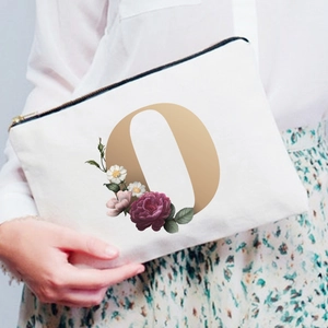 Detail of canvas makeup bag featuring letter O with floral peony and gold zipper detail