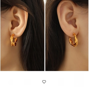 Detailed view of large gold twisted rope C-shaped hoop earrings worn on ears