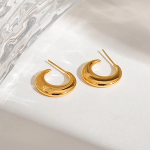 Minimalist 18K gold stainless steel crescent moon earrings with polished finish on water backdrop