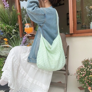 Détail du cabas à carreaux vert clair avec texture plissée porté par un mannequin dehors