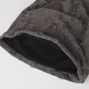 Detail of distressed mesh fabric with irregular holes and sparkling silver rhinestones