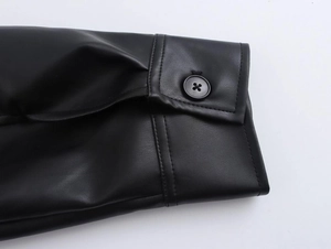 Detail of single black button and stitching on the faux leather jacket sleeve cuff