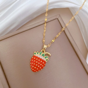 Detail of strawberry pendant with red enamel, green crystals and gold chain in gift box