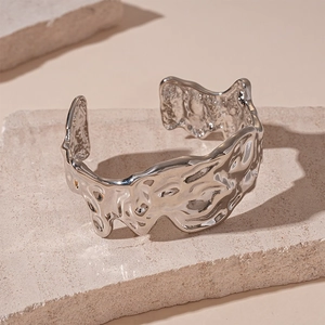 Detail of silver liquid metal bangle with irregular molten texture on stone base