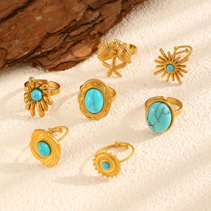 Close-up of bohemian gold rings with turquoise stones featuring shell and starfish designs