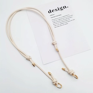 Detail of adjustable beige woven leather bag strap with polished gold metal buckles