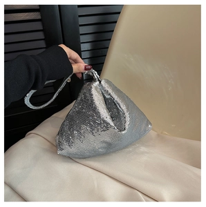 Gros plan d'un sac à bandoulière argenté à paillettes en forme de triangle tenu par un mannequin