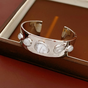 Détail d'un bracelet manchette argenté orné de cinq pierres naturelles blanches incrustées