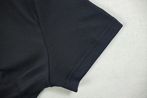Detail shot of the sleeve cuff stitching and texture on a black knit mini dress