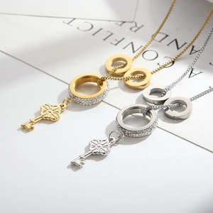 Dual-tone stainless steel key pendant necklace with sparkling crystal circles on book page