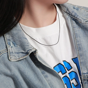 Close-up of a minimalist black thin cord necklace worn by a model in casual wear