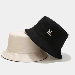 Dettaglio del ricamo lettera M su cappelli alla pescatora neri e beige