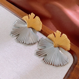 Detailed macro shot of bicolor ginkgo leaf earrings with gold and silver texture finish