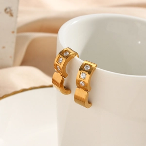 Detailed view of 18K gold plated square zircon hoop earrings on a white ceramic cup