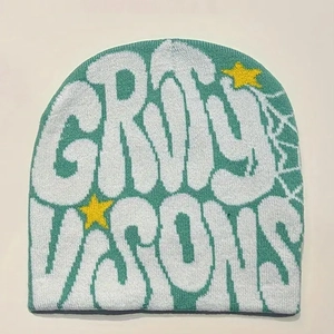 Detail of mint green knit beanie featuring white graffiti letters and yellow star embroidery