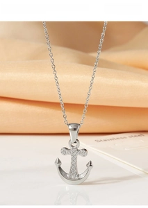 Macro view of a silver nautical anchor pendant in titanium steel with zircon crystals
