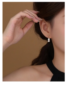 Macro close-up of elegant double white pearl earrings with gold metallic finish