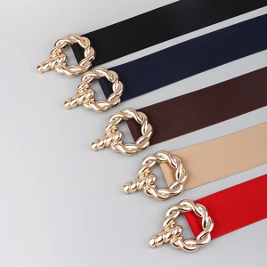 Detail of five elastic waist belts with golden twisted buckles in multiple colors