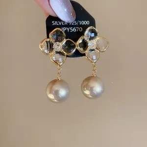 Detail of flower earrings with gold-plated petals, zircons, and double champagne pearls