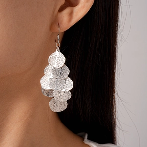 Detail of silver hollow geometric leaf earrings showing layered texture and tassel drop