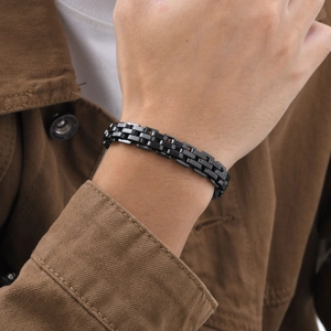 Close-up of a sleek black stainless steel wide watchband style bracelet on a male wrist