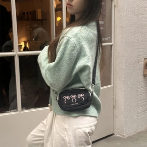 Detail of black nylon crossbody bag with pink ribbon embroidery and silver hardware
